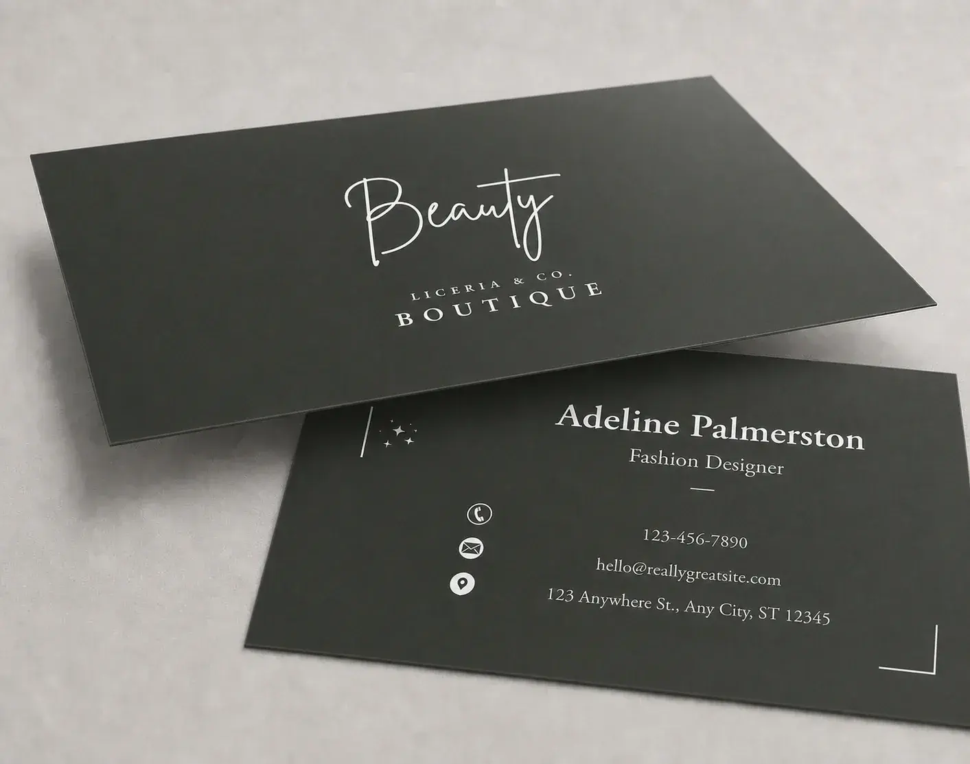 Two dark green laminated business cards with a white script logo, lying at an angle