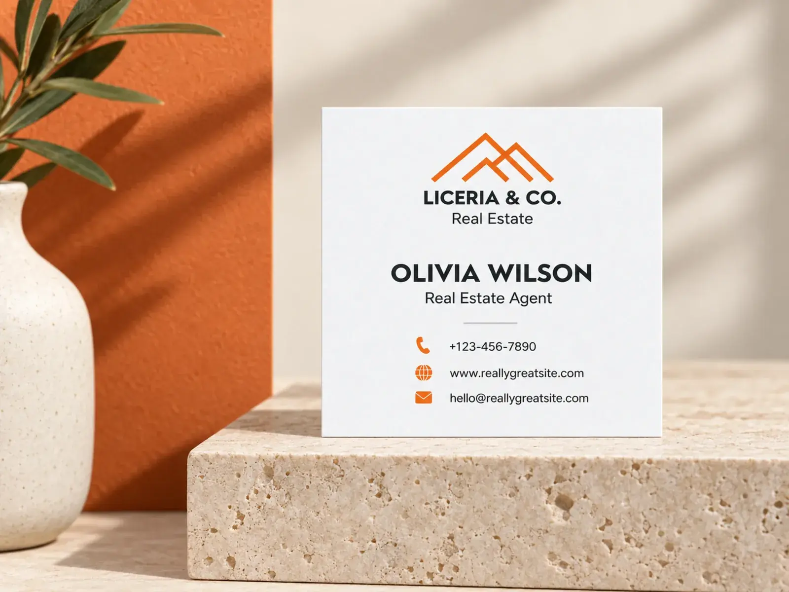 A square matte laminated business card standing on stone beside a vase