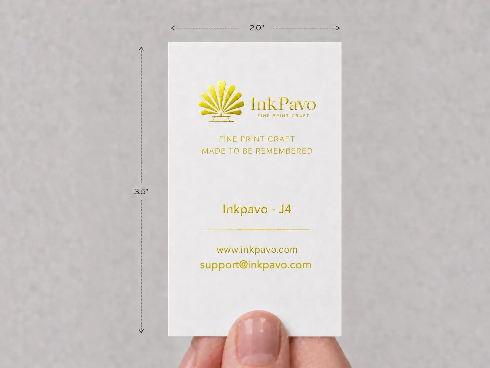 A hand holding an upright white card with the InkPavo logo hot-foil stamped in Bright Gold