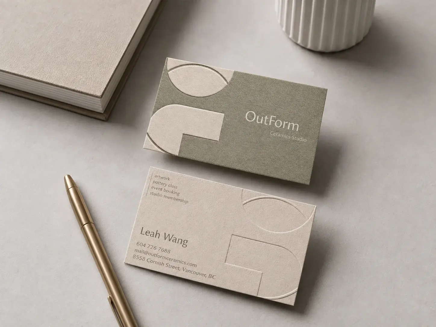 Letterpress business card: Beige Montericca cotton with a warm grey-green Pantone flood on the front, where ivory half-circle and block shapes sit on the left and a light ivory wordmark on the right; the back repeats the shapes in blind deboss beside a warm grey services list, name and contact lines.