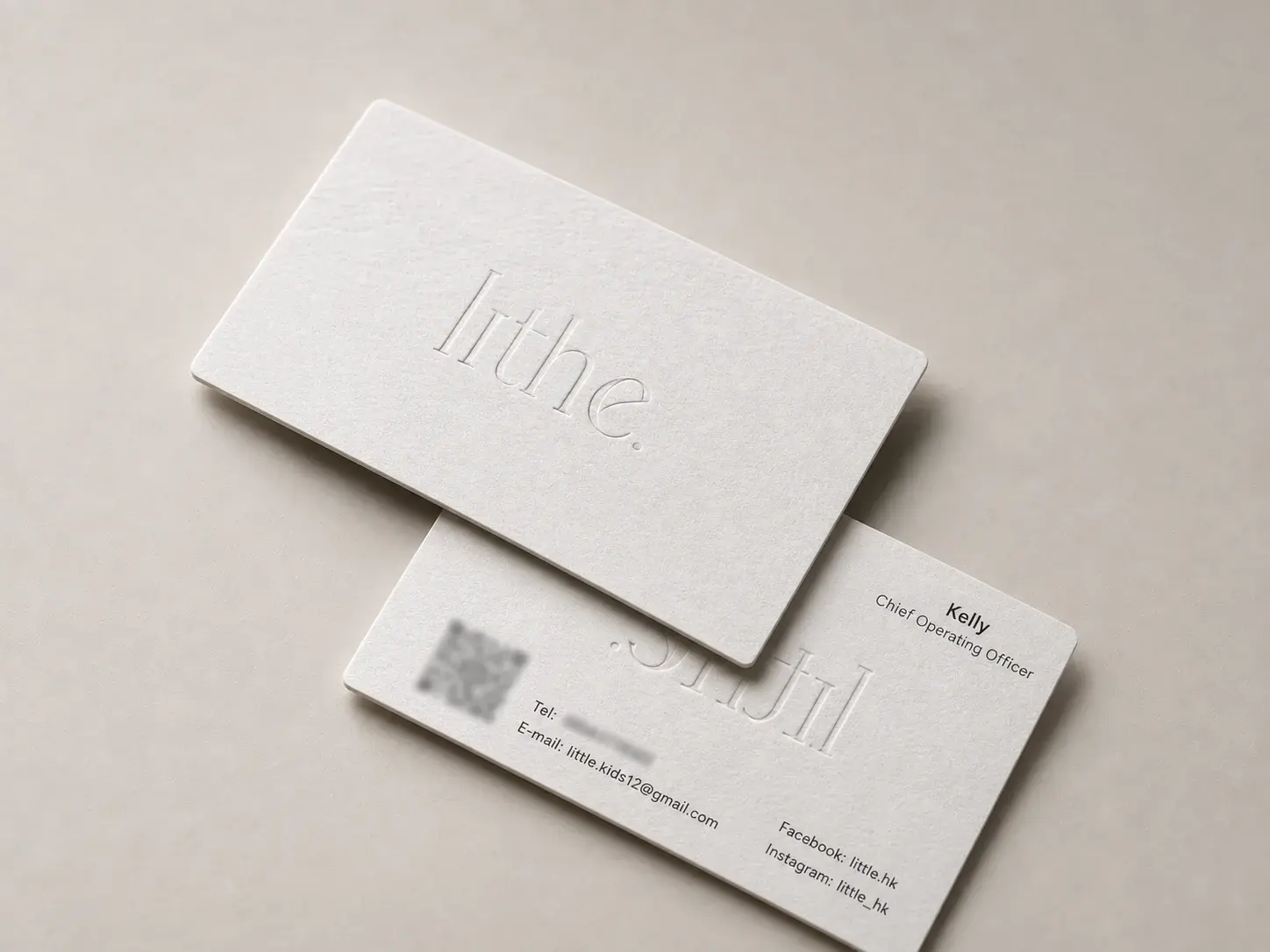 Letterpress business card: White Wilde 450 cotton with rounded corners and a large lowercase light serif wordmark ending in a full stop, blind-debossed in the center of the front; the back has a small black sans name and title top right, a QR code with phone and email bottom left, and social handles bottom right.