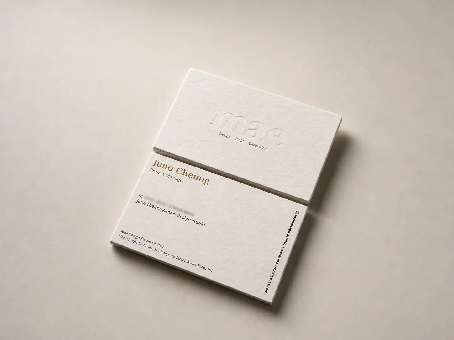 Letterpress business card: White Wilde cotton with a large blind-debossed lowercase serif wordmark over an aged-gold foil services line; the back has a bold serif name and title in aged-gold foil, black contact and address lines on the left, and an Instagram handle and website set vertically down the right edge.
