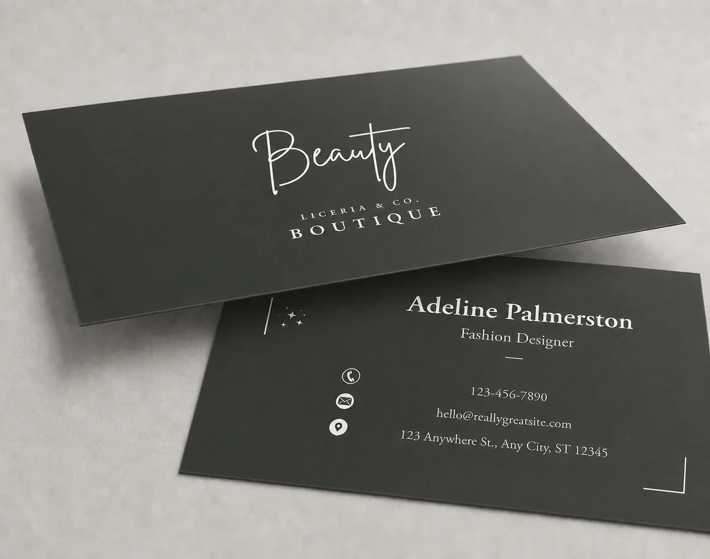 Two dark green laminated business cards with a white script logo, lying at an angle