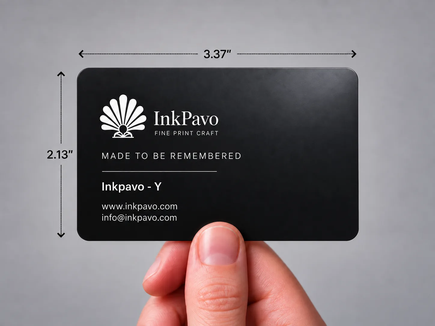 A hand holding a black InkPavo PVC card, marked 3.37 × 2.13 in